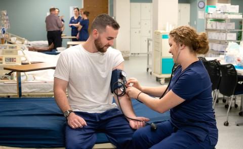 A nursing student takes another student's blood pressure in UNE's Interprofessional Simulation and Innovation Center